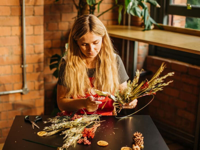 A woman making a festive wreath from dried foliage